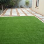 Landscaping job: a square of bordered artificial lawn surrounded by paving